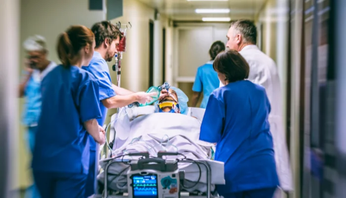 Médicos e enfermeiros com paciente em maca, representando períodos de carência para internações.