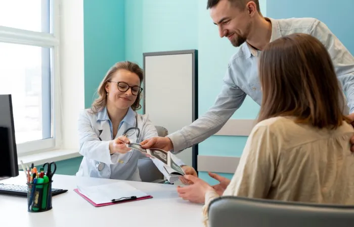 Três pessoas conversam e sorriem em um consultório médico.