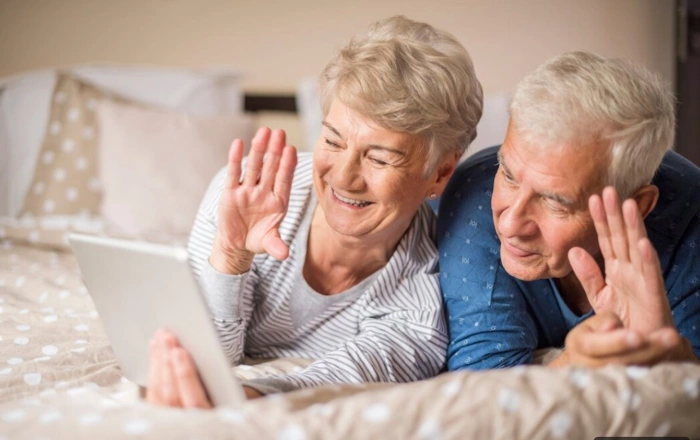 Casal de idosos assiste algo em tablet, representando reajuste de plano de saúde para idosos.