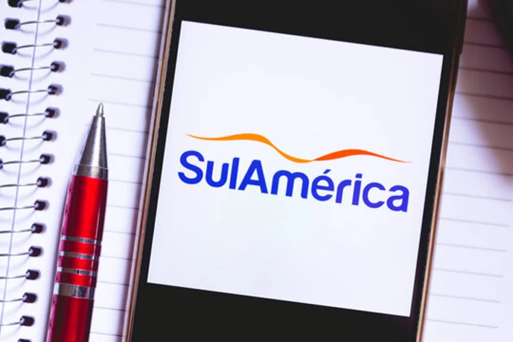 Logomarca da SulAmérica Saúde na tela de um celular. Há uma caneta ao lado do telefone. Falando sobre como funciona o plano de saúde sulamérica.