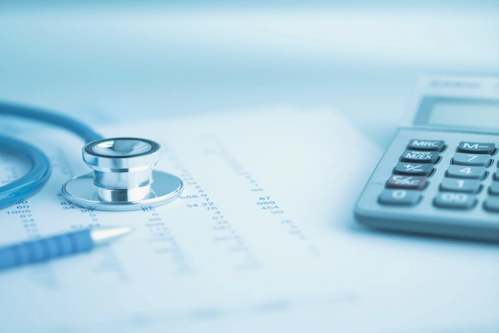 Estetoscópio e calculadora sobre documentos. Explicando como pedir reembolso sulamérica saúde após cirurgia.
