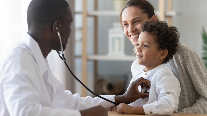 Médico examina criança que está no colo da sua mãe. Falando sobre se o plano sulamérica é um bom plano de saúde.
