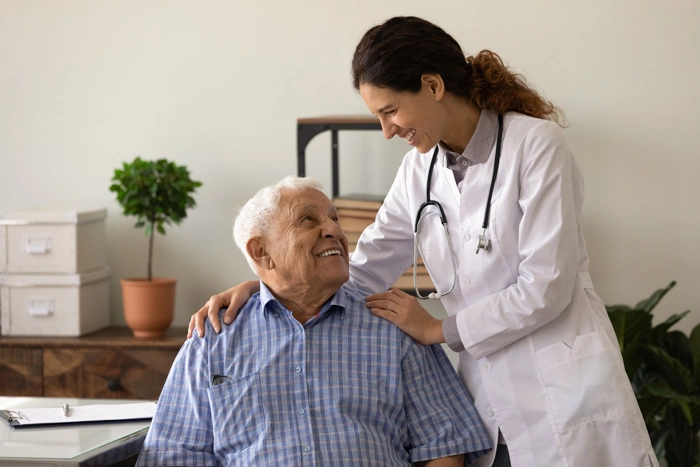 Profissional de saúde dá assistência a idoso. Falando sobre plano de saúde vitalício.