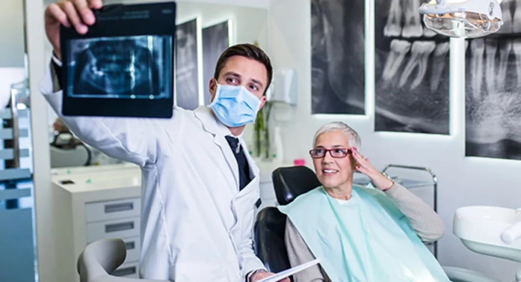 Dentista mostra resultado de raio-x a paciente. Falando sobre plano de saúde para dentistas.