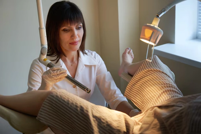Médica usa instrumento luminoso para observar região íntima de paciente. Explicando se plano de saúde cobre laser íntimo.