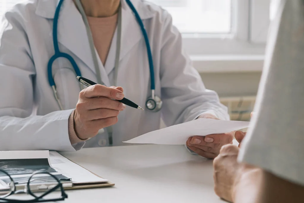 Médico explica algo a um paciente com um documento em mãos. Falando dos planos de saude no rs.